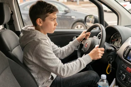 Jeune adolescent de 14 ans au volant d'une voiture sans permis, concentré sur la route, intérieur de véhicule réaliste