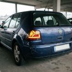 Feu arrière LED moderne installé sur une voiture compacte des années 2000, vue arrière trois quarts en parking urbain