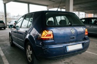 Feu arrière LED moderne installé sur une voiture compacte des années 2000, vue arrière trois quarts en parking urbain