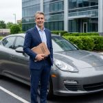 Homme d'affaires confiant avec Porsche Panamera en ville