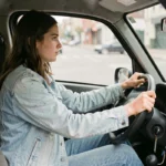 Jeune conductrice au volant d'une voiture sans permis en ville, illustrant les conditions légales pour conduire une VSP