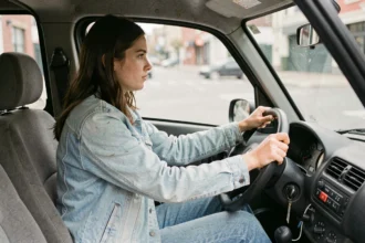 Jeune conductrice au volant d'une voiture sans permis en ville, illustrant les conditions légales pour conduire une VSP