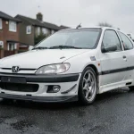 Peugeot 306 Maxi en occasion vue de trois quarts avant, montrant des détails d'usure typiques d'un véhicule d'occasion comme des éclats de peinture et de légères traces de rouille