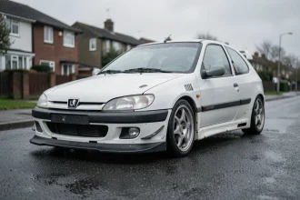 Peugeot 306 Maxi en occasion vue de trois quarts avant, montrant des détails d'usure typiques d'un véhicule d'occasion comme des éclats de peinture et de légères traces de rouille