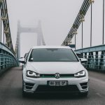 a white car driving across a bridge on a foggy day