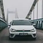 a white car driving across a bridge on a foggy day