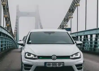 a white car driving across a bridge on a foggy day